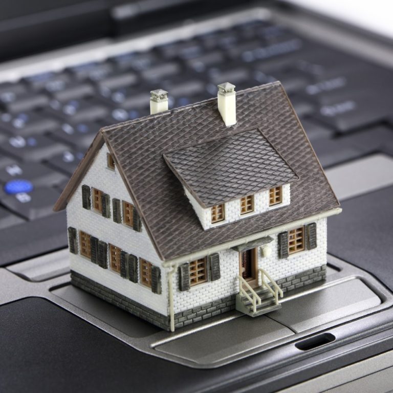 Ein kleines Modell eines Hauses steht auf einer Laptop-Tastatur.