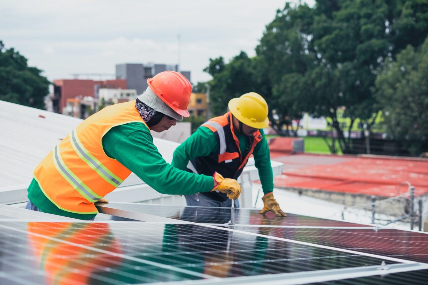 Zwei Arbeiter installieren Solarpanels auf einem Dach.
